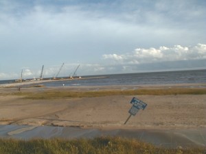 Sign: STORM DEBRIS IN WATER DO NOT ENTER Note pile drivers working on bridge in background